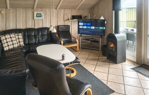 Uma sala de estar acolhedora com sofá de couro, televisão, lareira e parede de madeira.