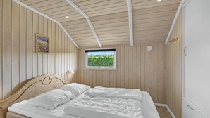 A bedroom with a wooden ceiling, a bed with white bedding, a window with a view of greenery, and a wall-mounted lamp. - 3 bedroom amazing home in Haderslev (Haderslev)