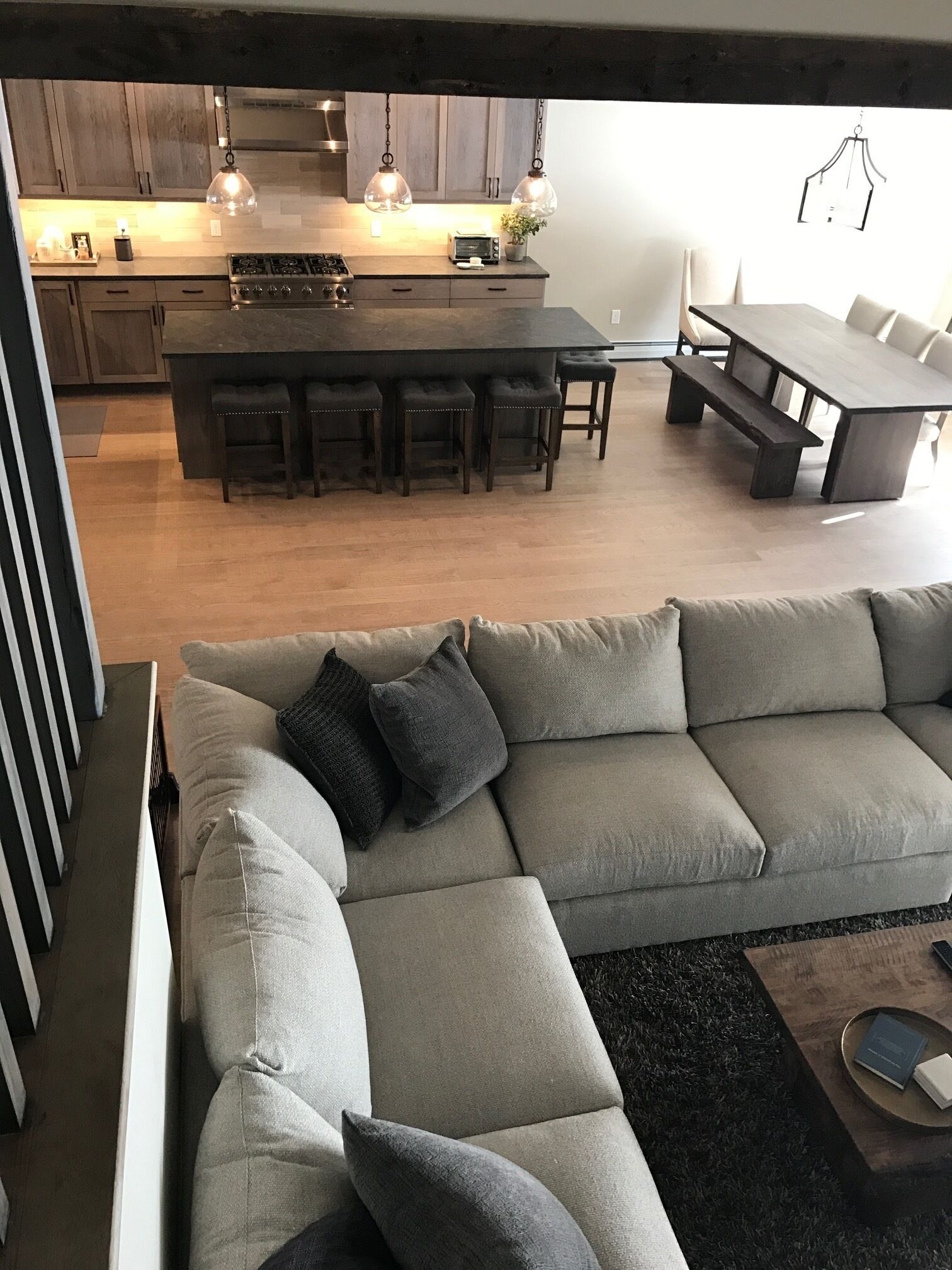 A modern kitchen with a central island, bar stools, and pendant lighting.
