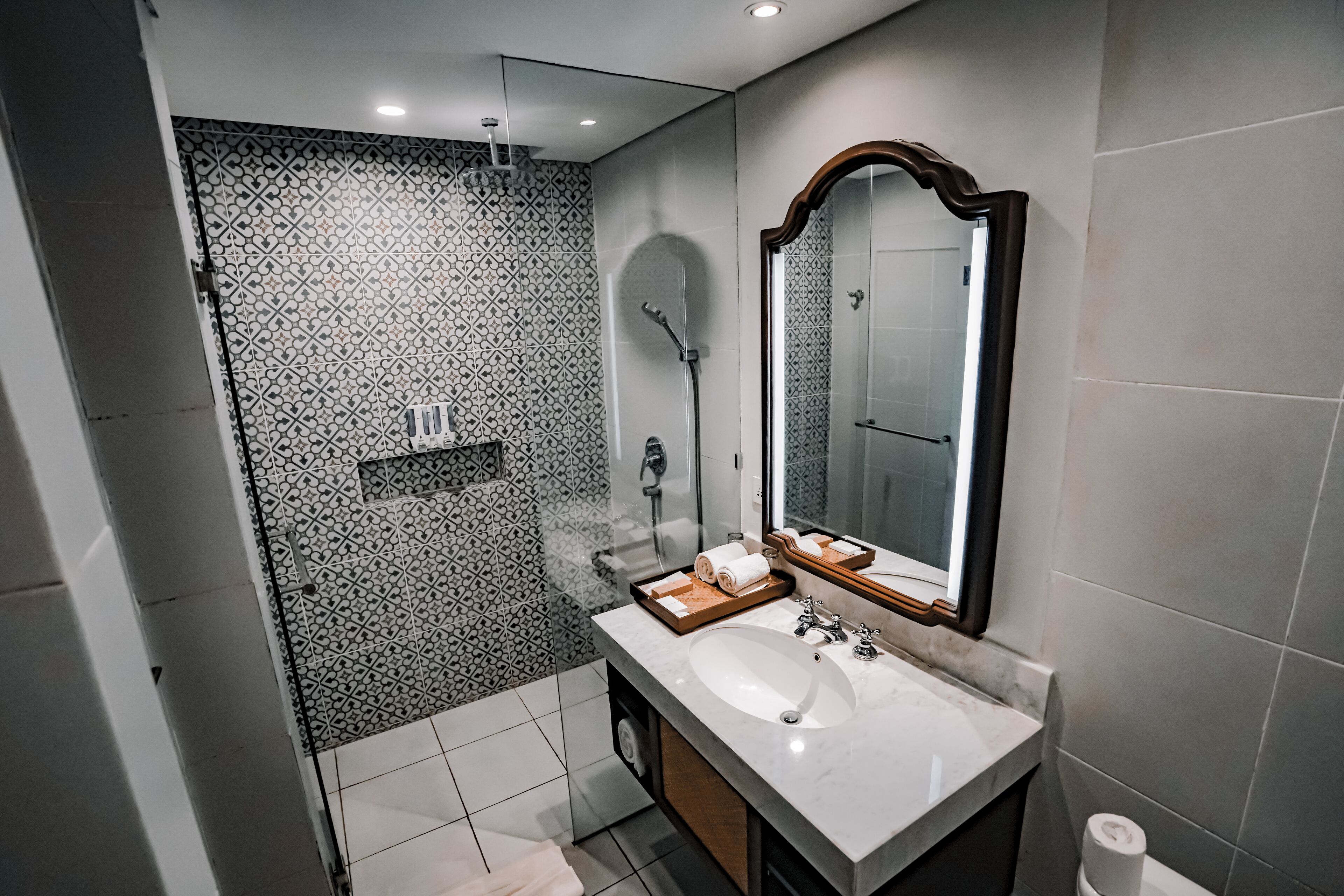 Un baño moderno con un espejo grande, un lavabo y una zona de ducha.