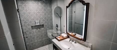 Un baño moderno con un espejo grande, un lavabo y una zona de ducha.