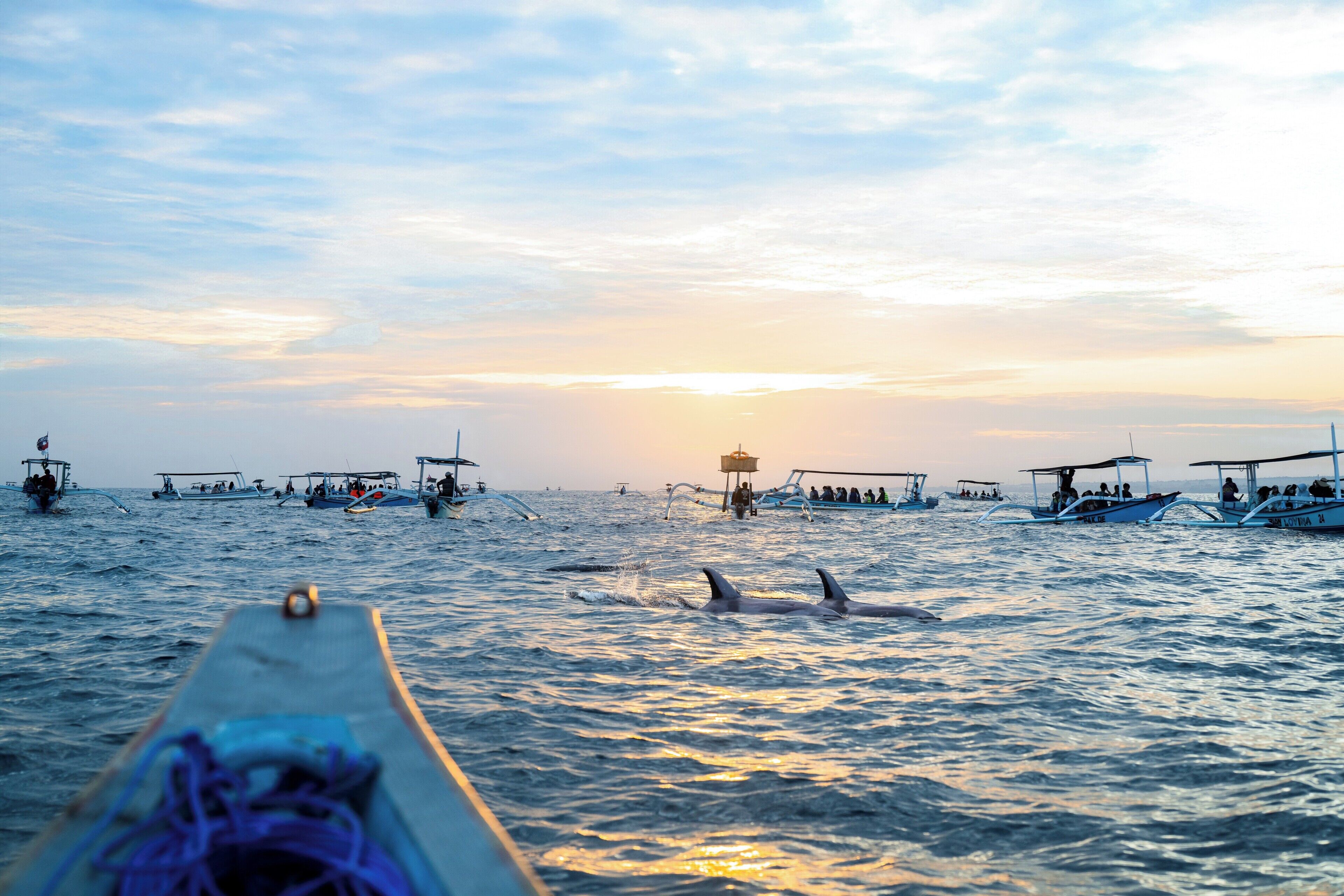 Um barco com pessoas na água durante o pôr do sol.