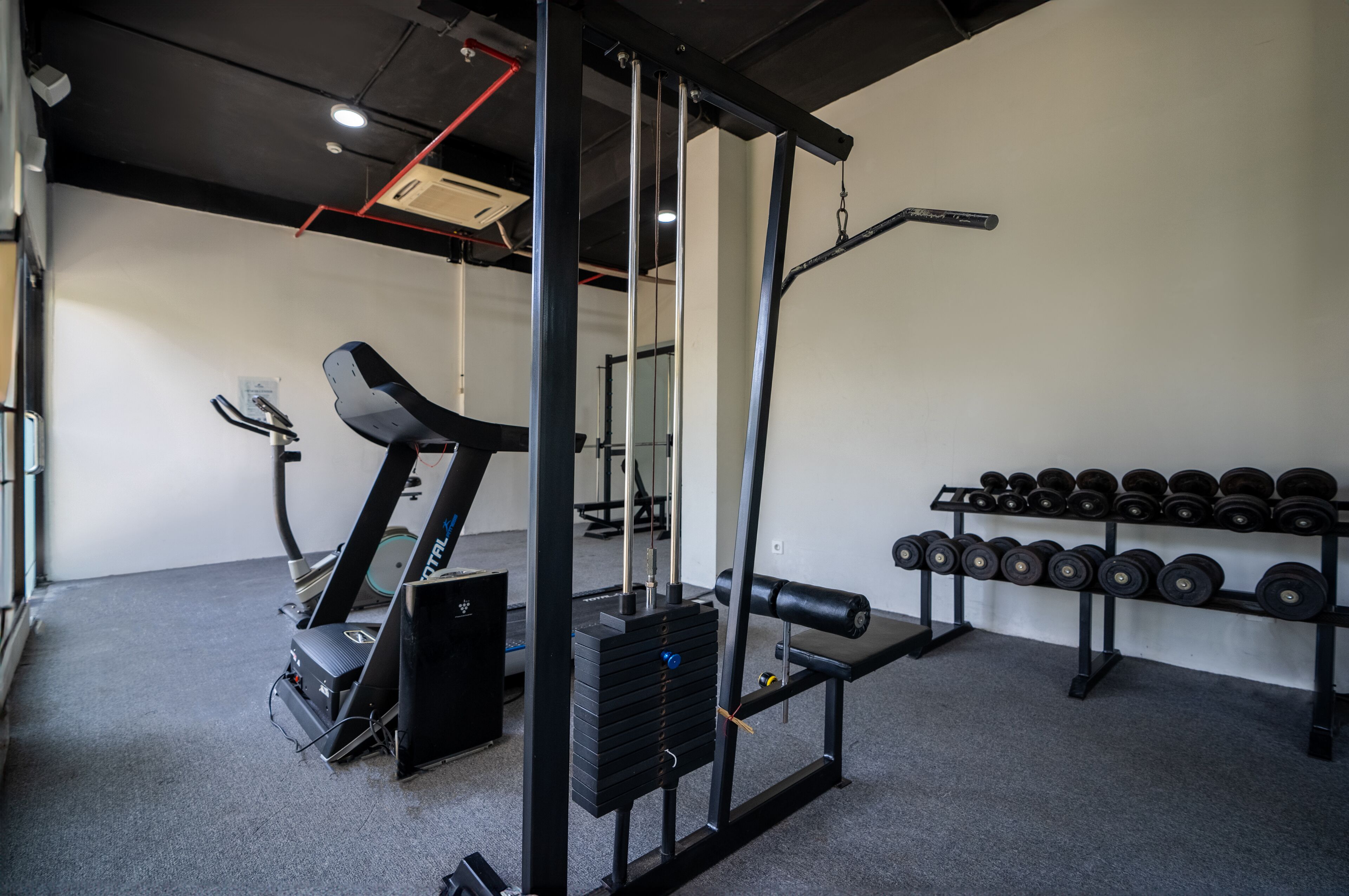 Un gimnasio con equipo de ejercicio, una cinta de correr y un estante con mancuernas.