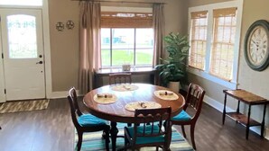 A dining room with a round wooden table, four chairs, and a ceiling fan.