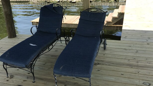 A wooden deck with two blue lounge chairs and a wooden table.