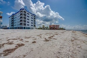 En strand med et hotel og en bygning i baggrunden.