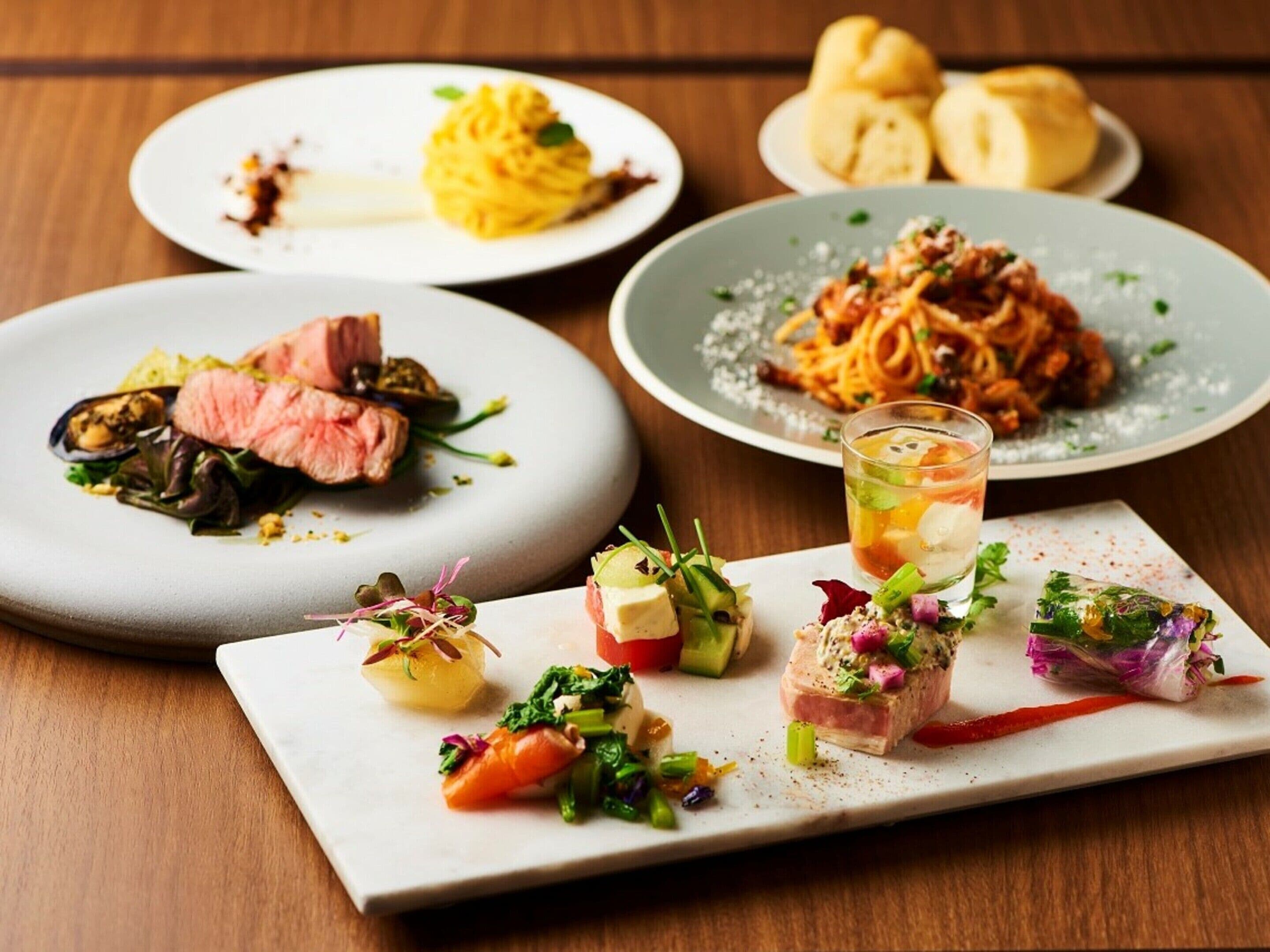 A variety of dishes on plates, including pasta, steak, and appetizers.