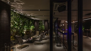 Un jardín interior moderno con asientos y una zona de bar.