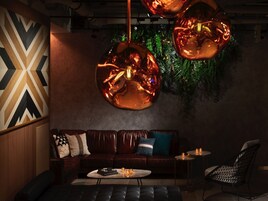 A modern lounge area with a leather sofa, a round coffee table, and a metal chair.