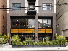 Un edificio moderno con una entrada destacada, ventanas amplias y plantas exteriores.