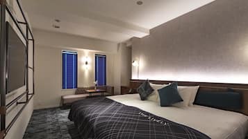 Una habitación de hotel con una cama grande, un área de descanso con mesa y un televisor montado en la pared.