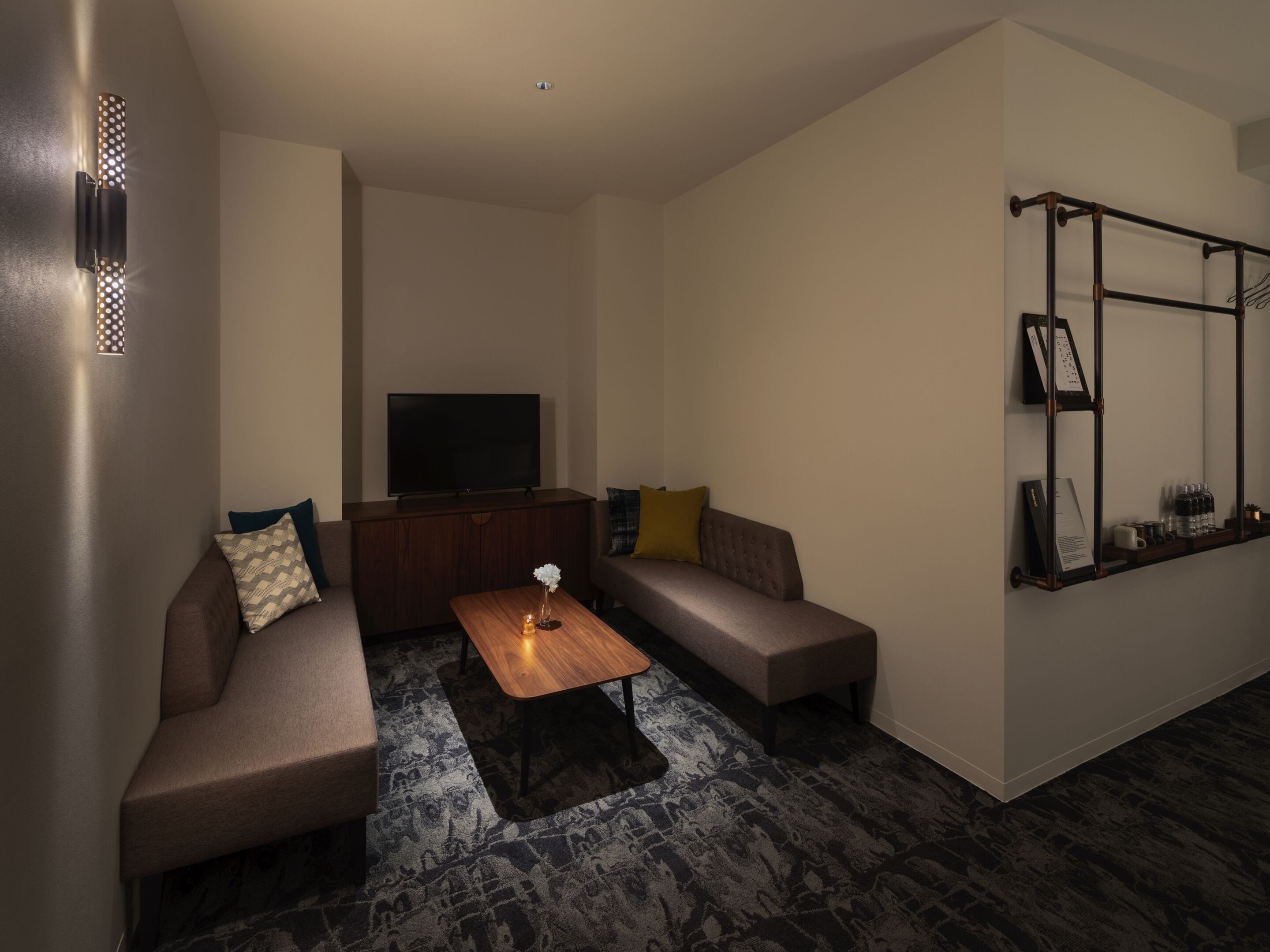 A modern living room with a sectional sofa, a flat-screen TV, a coffee table, and a built-in shelf with decorative items.