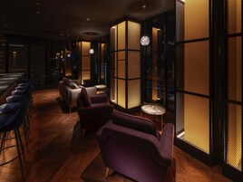 A dimly lit lounge area with wooden flooring, a sofa, and a small round table.