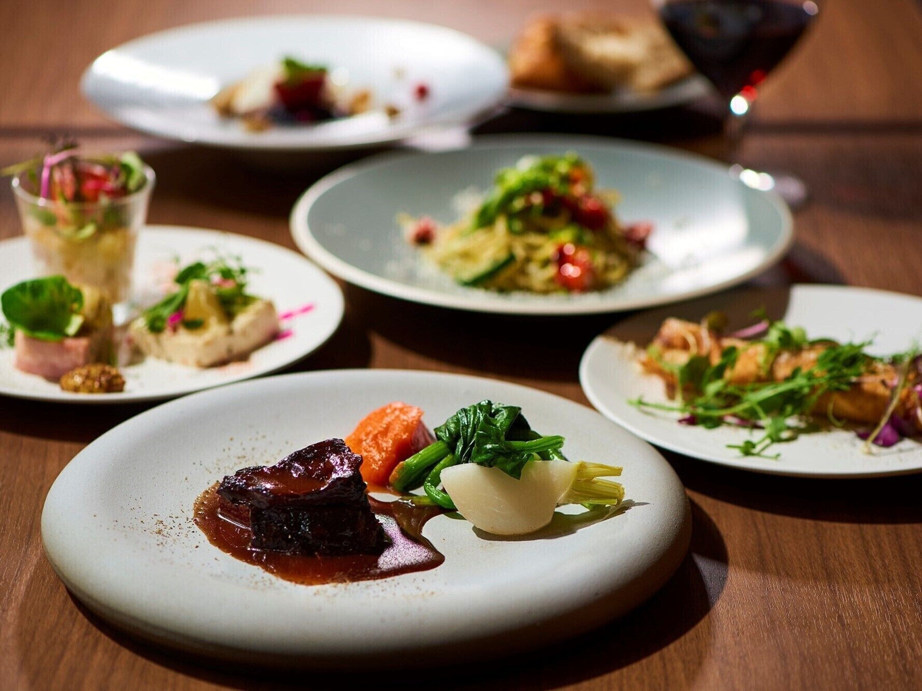 Una mesa con varios platos, incluyendo un plato con bistec y verduras, y otros platos con distintas comidas.