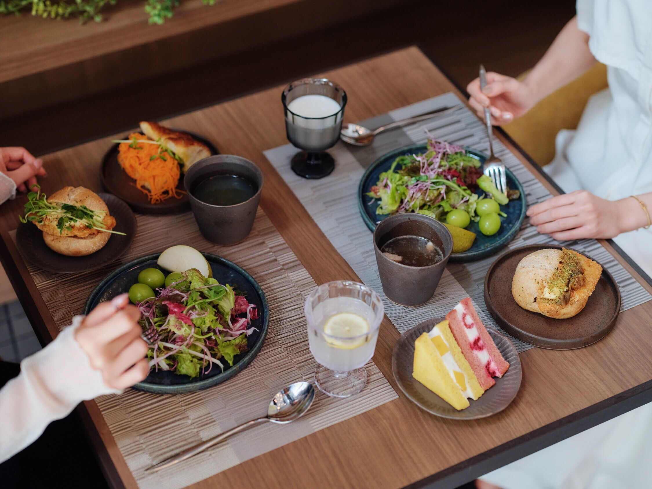 Una mesa de comedor con diversos platos, como una ensalada, un sándwich y un postre.