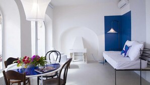 Et moderne, minimalistisk værelse med spiseplads, sofa og et stort vindue.