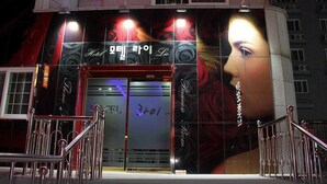 A building facade with a large mural, metal railings, and a door with a number. - Hotel Lie (Geoje)