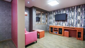 A modern room with a pink sofa, a wooden entertainment unit, and a flat-screen TV mounted on a multicolored wall. - Hotel Lie (Geoje)