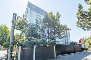 Um edifício moderno com portão fechado, rodeado por árvores e céu claro.