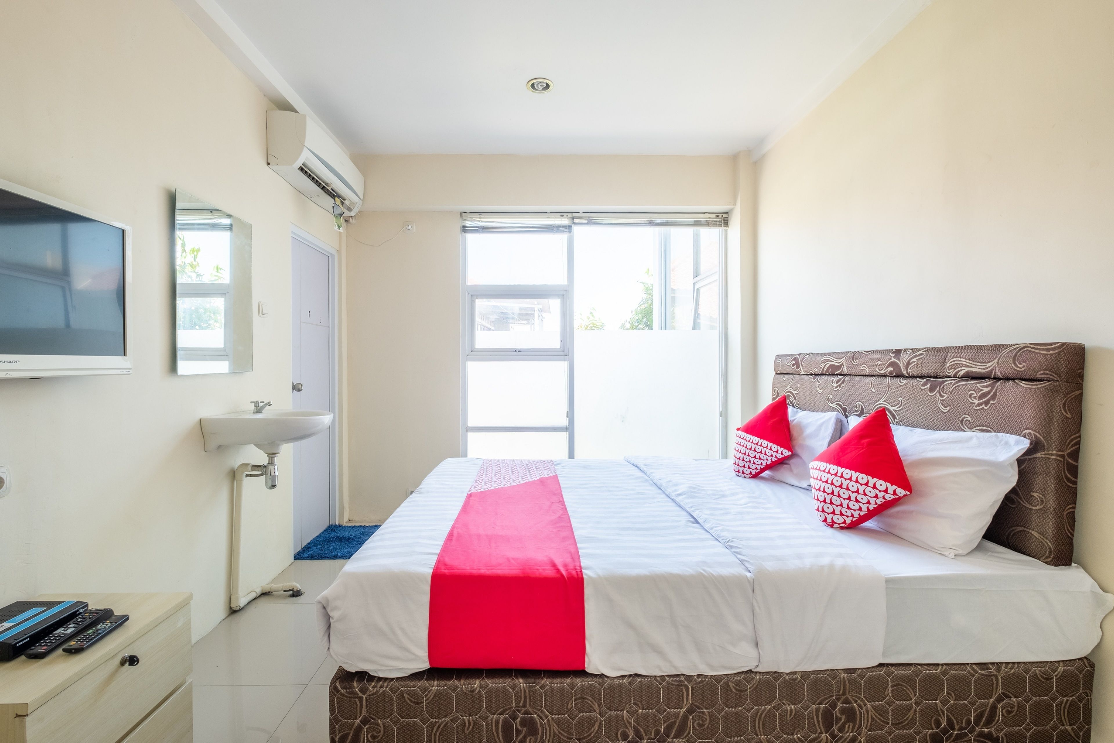 Una camera d'albergo con un letto, una TV, un lavandino e una finestra.