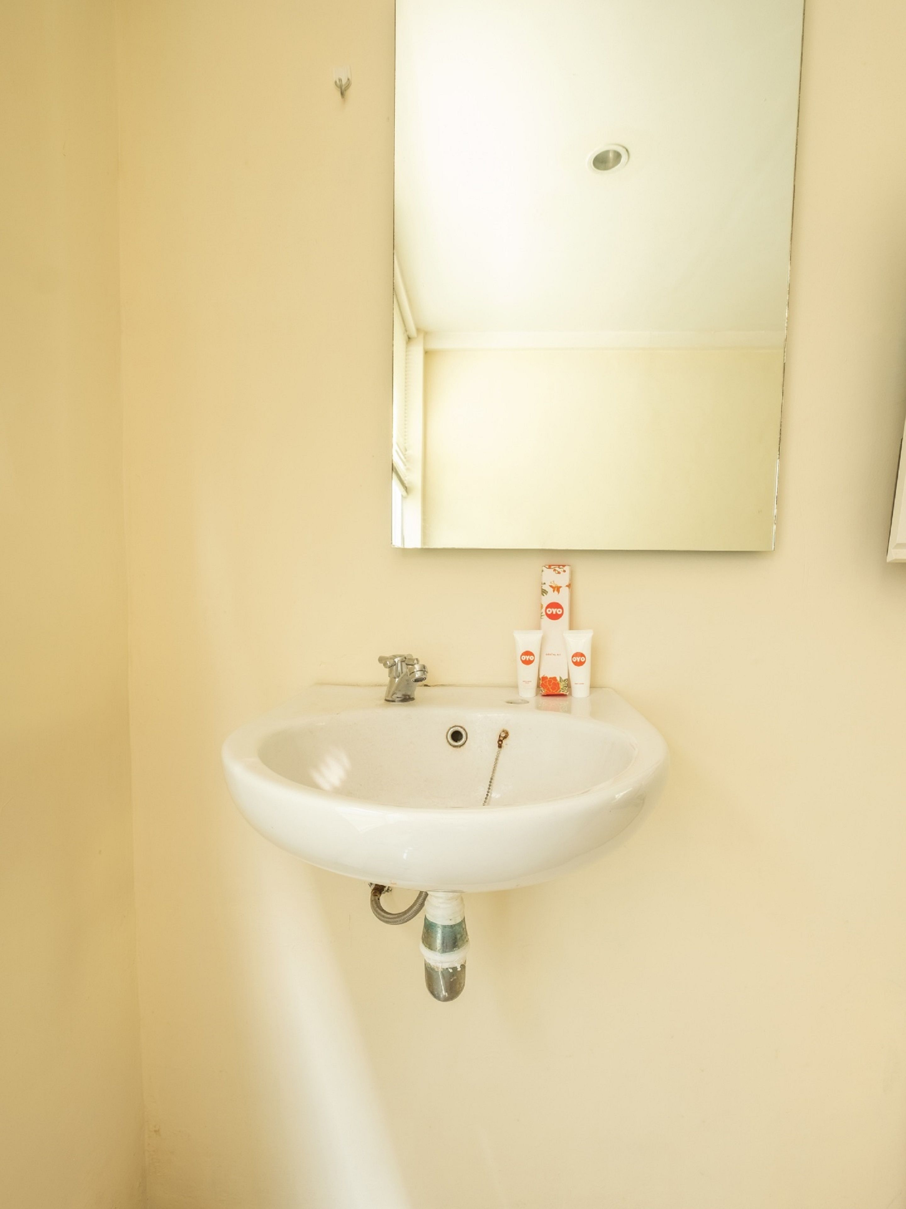 A bathroom with a white sink, a mirror above it, and toiletries on the sink.