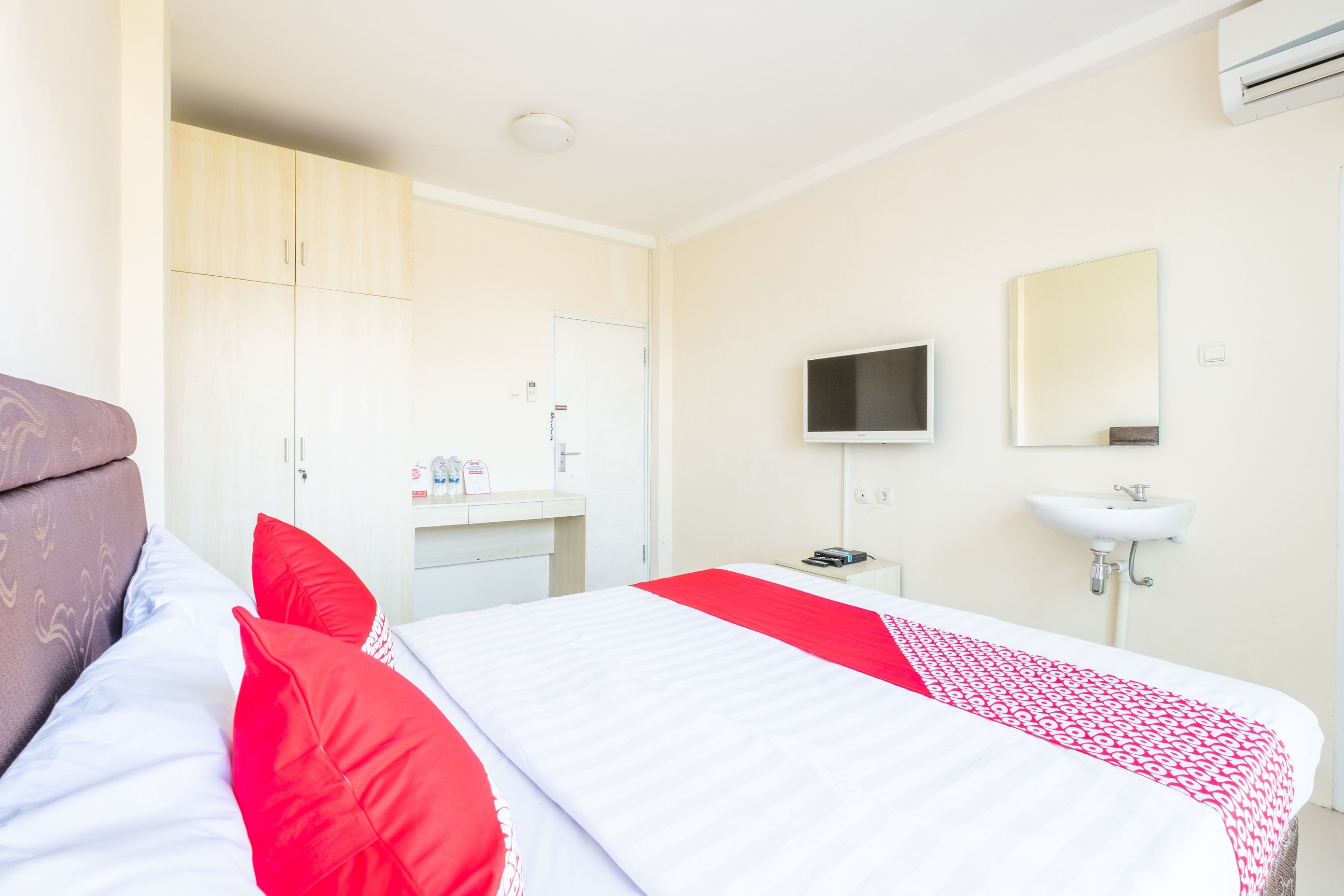 A hotel room with a bed, a TV, a sink, and a wardrobe.