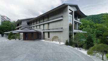 Stunning building with a central entrance and two wings, surrounded by a paved courtyard with lush greenery.