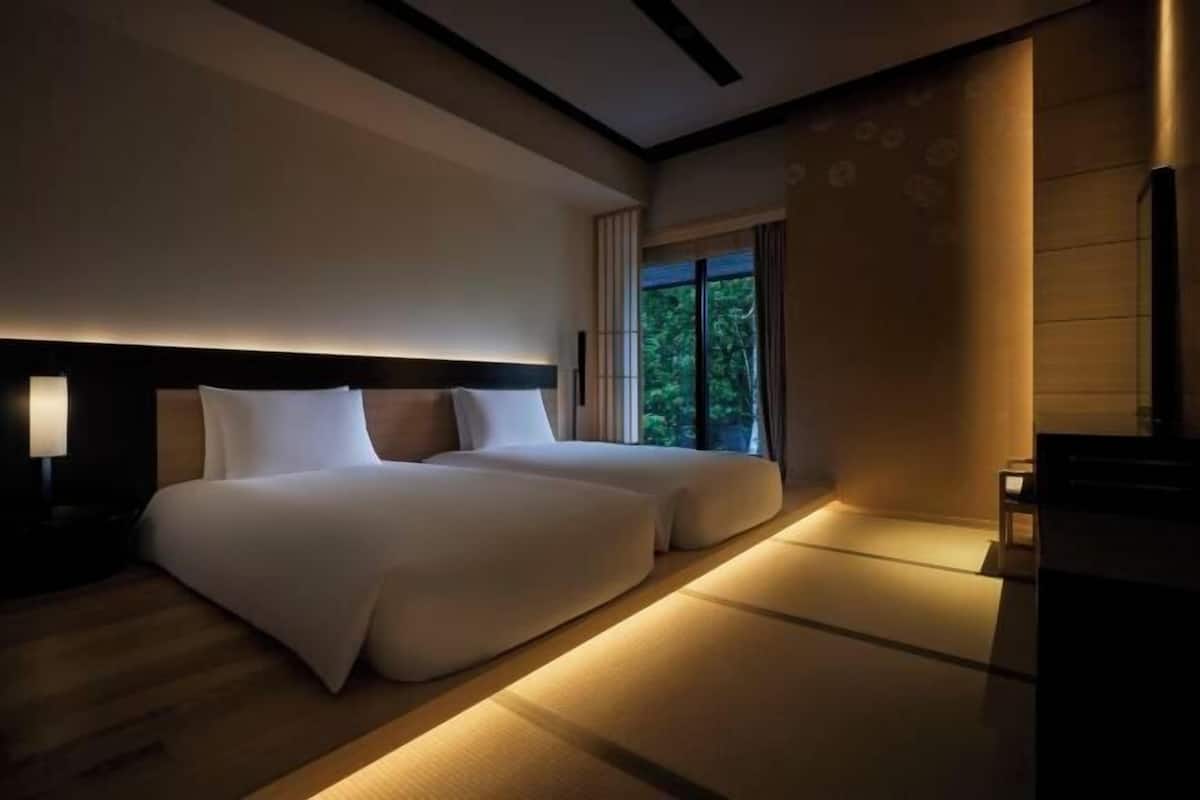 Habitación de hotel con una cama grande, una mesita de noche, una ventana con cortinas y vistas al exterior.