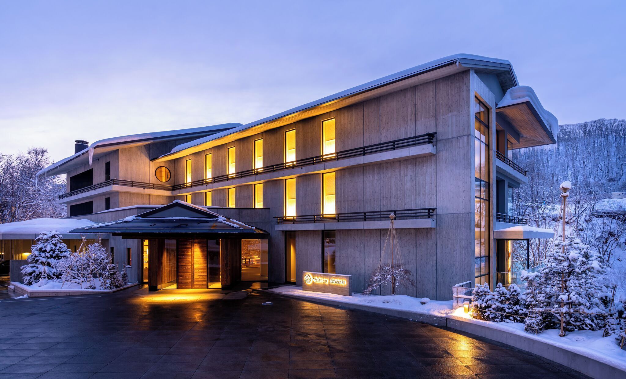 A modern hotel with a multi-story structure, a covered entrance, and a snow-covered landscape.