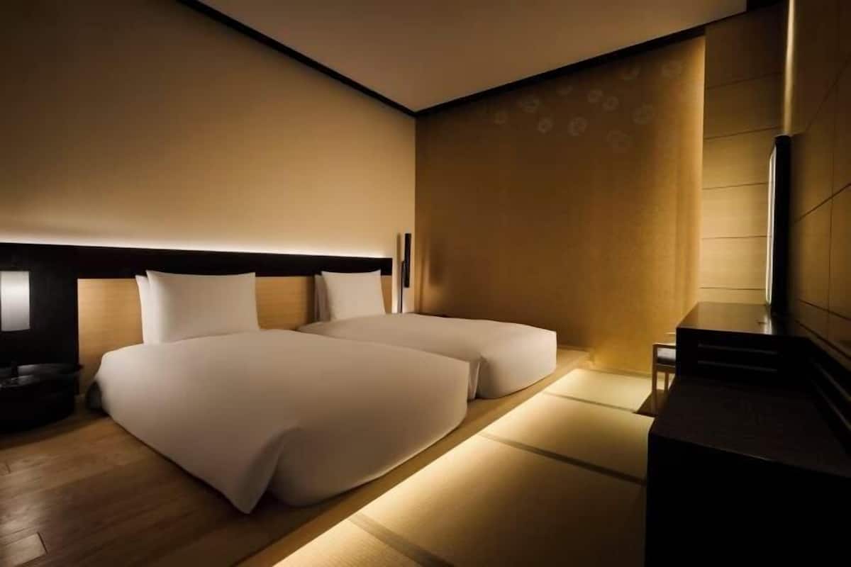 Una habitación de hotel moderna con una cama grande, un pequeño rincón de descanso y un escritorio.