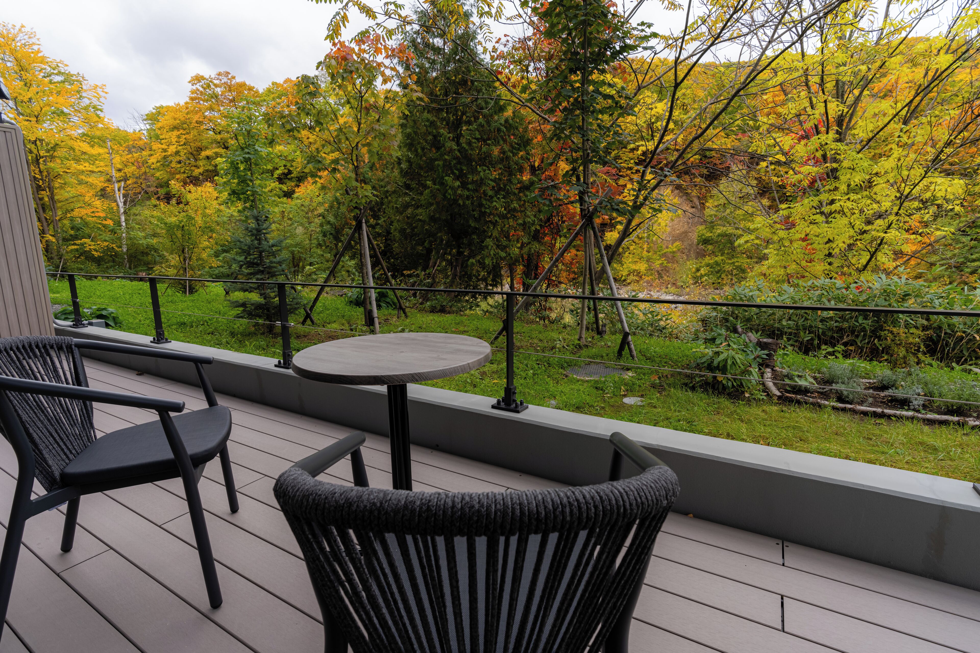 A deck with outdoor seating and a view of autumn foliage.