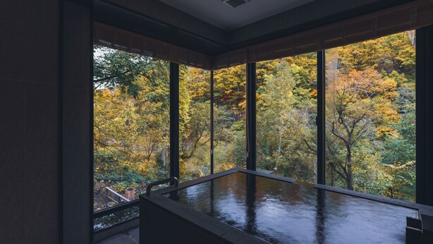 Un intérieur moderne doté de grandes fenêtres qui offrent une vue sur le feuillage automnal.