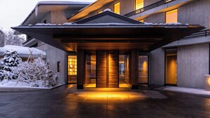 Un bâtiment moderne doté d’un porche, de portes en bois et surplombant un paysage enneigé.