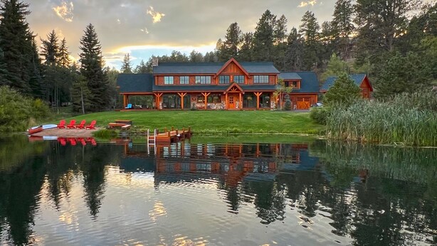 A large lodge with a reflective lake in front, surrounded by trees. - Spectacular Waterfront Home in the Mountains.  Welcome to Green Valley Lodge! (Conifer)