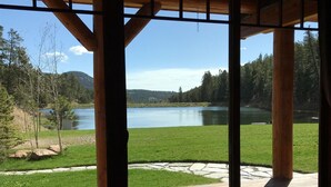 A wooden deck with a view of a lake and forest. - Spectacular Waterfront Home in the Mountains.  Welcome to Green Valley Lodge! (Conifer)