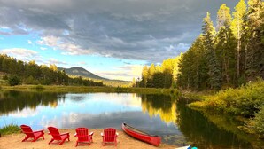 A lakeside setting with red chairs and canoes on the shore. - Spectacular Waterfront Home in the Mountains.  Welcome to Green Valley Lodge! (Conifer)