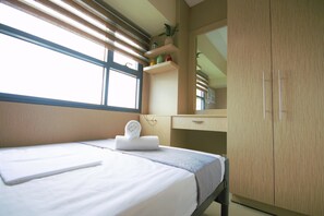 A hotel room with a bed, a desk, a mirror, and a wardrobe.