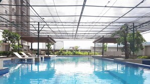 Une piscine intérieure à l’eau d’un bleu limpide, entourée de chaises longues et de plantes en pot.