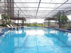 An indoor swimming pool with clear blue water, surrounded by lounge chairs and potted plants.