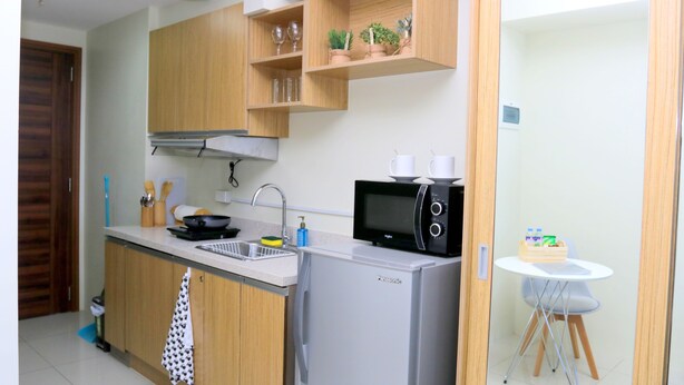 Une cuisine compacte dotée de meubles en bois, d’un réfrigérateur, d’un four à micro-ondes et d’un petit coin repas avec une table et une chaise.