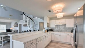 A modern kitchen with white cabinetry, a stainless steel refrigerator, and a built-in microwave. - Beachside Living: Family Retreat in Galveston (Galveston)