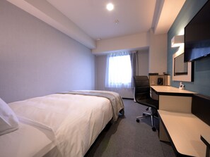Hotelkamer met een groot bed, een bureau, een stoel, een televisie en een raam met gordijnen.