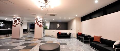 A modern reception area with a check-in desk, seating area, and a central decorative column.