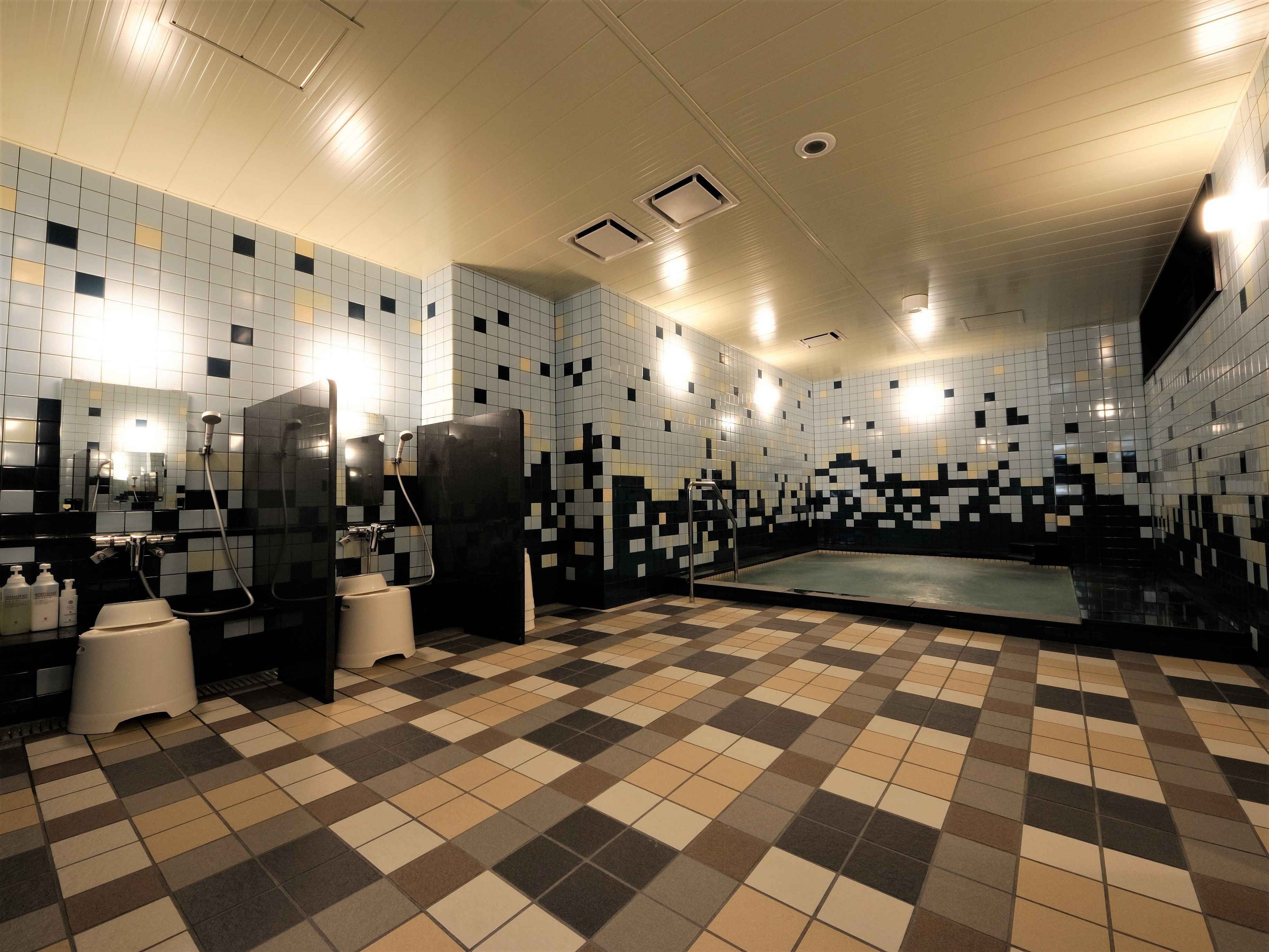 A bathroom with checkered floor tiles, a shower area, and a tiled wall with a pixelated pattern.