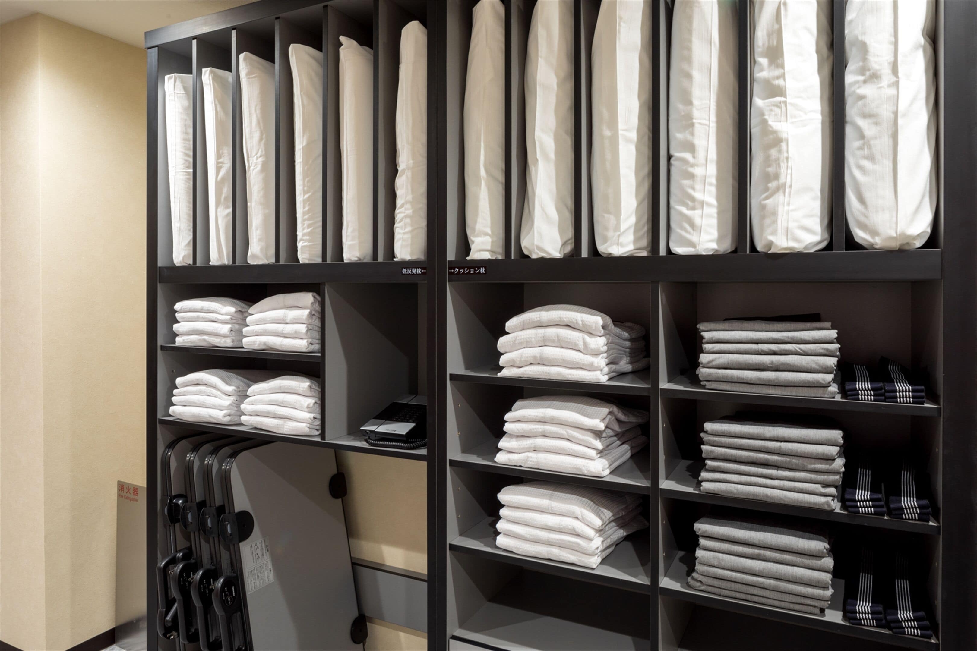 A neatly organized storage unit with shelves holding folded towels and linens.