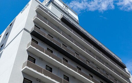 A modern hotel building with multiple balconies and a clear sky.