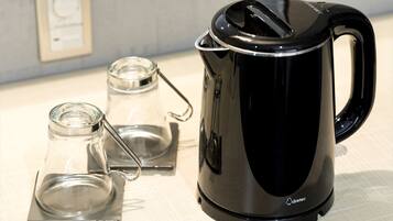 A black electric kettle with a glass carafe and a glass jug on a table.
