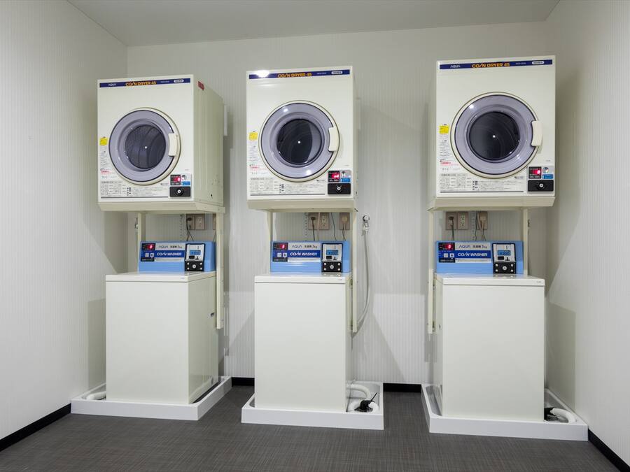 Tres lavadoras de carga frontal en línea, cada una con panel de control y toma de agua.