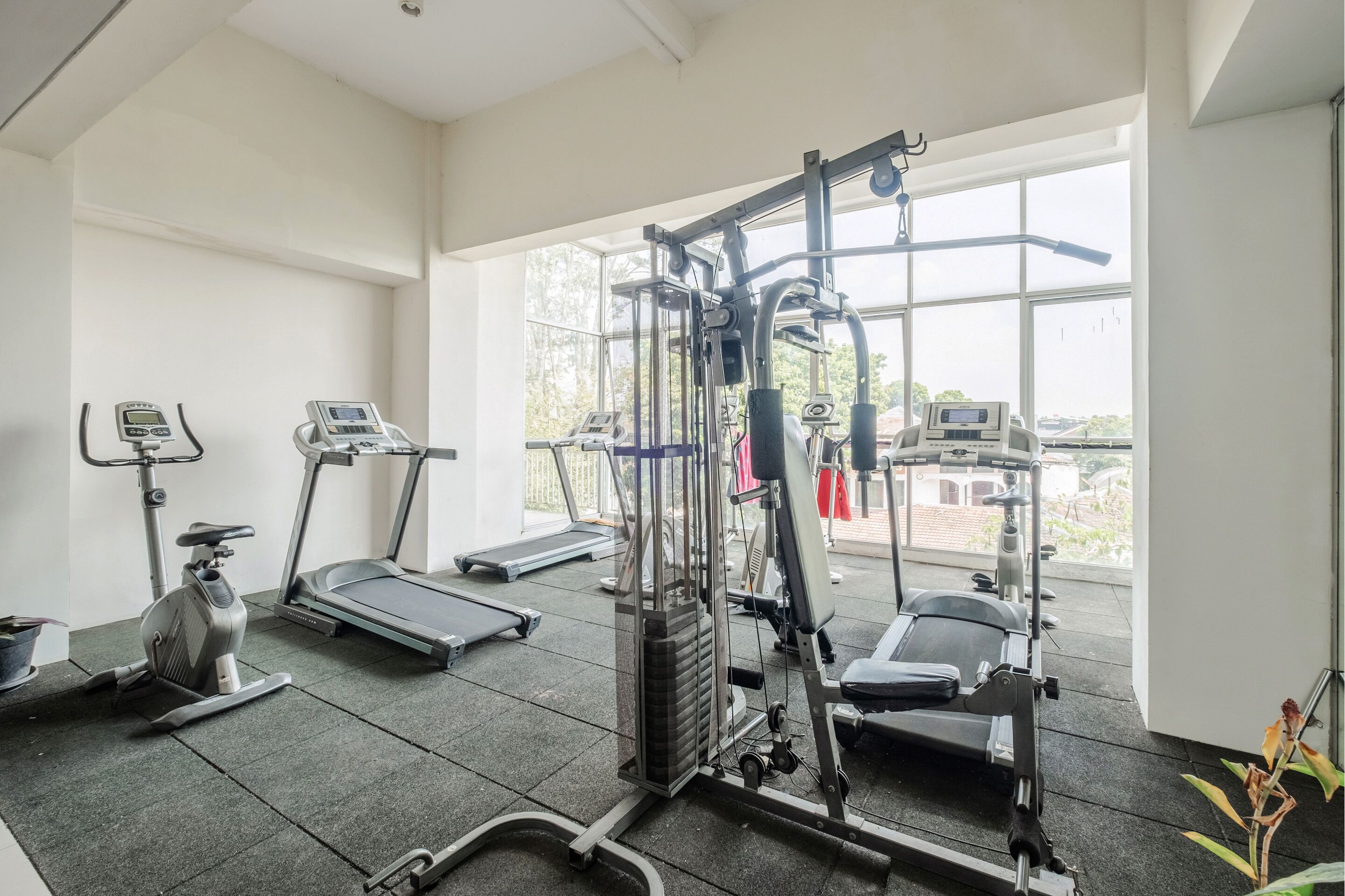 Une salle de sport équipée de tapis de course, d’un appareil elliptique et de machines de musculation.