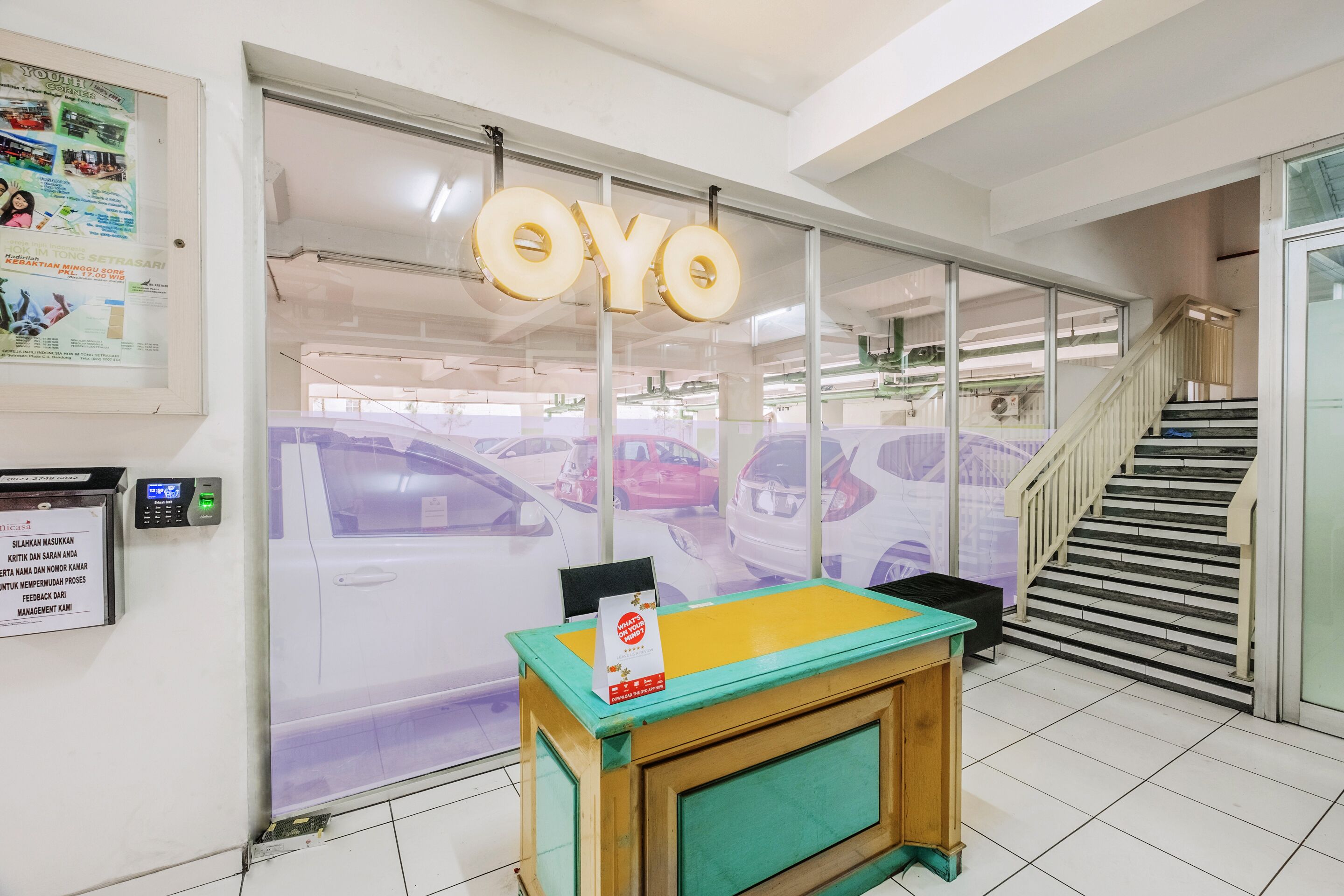A reception desk with a sign that reads "OYO" in front of a glass door.